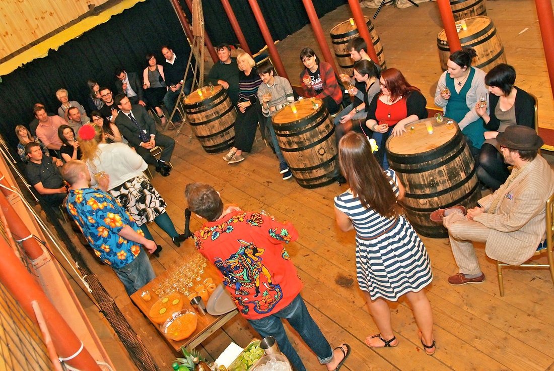 A whisky tasting event with barrels and a large group